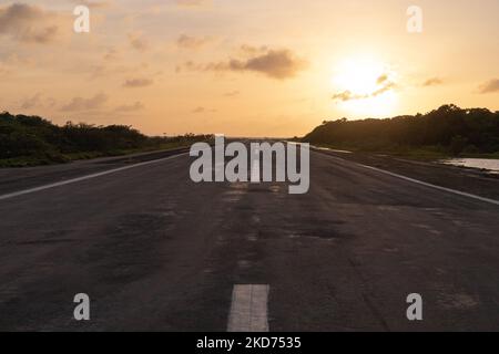 La grande route menant à l'aéroport au Venezuela Los Roques avec un coucher de soleil doré dans le backrgound Banque D'Images