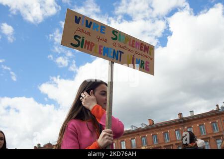 Une jeune femme tient une lecture de carton "vivre simplement pour les autres pourrait simplement vivre". La veille du premier tour de l'élection présidentielle française, des centaines de collectifs ont appelé à « l'arche de l'avenir » dans toute la France pour rappeler aux candidats à la présidence toute la crise qui se produit maintenant : climat, biodiversité, guerres, inégalités croissantes, santé, Extinction des espèces, etc. À Toulouse, plus de 30 organisations ont appelé à la « arche pour l'avenir » (NousToutes, XR, YFC, Greenpeace...) et à former une chaîne humaine. Plusieurs milliers de personnes sont venues et ont formé une chaîne humaine pour aller jusqu'au tow Banque D'Images