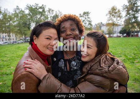 Trois amies souriantes et multiraciales se sont embrassée lors d'une promenade dans le parc de la ville. Banque D'Images