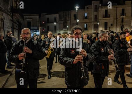 Membres de la bande pendant la procession avec la croix qui rencontre le premier crucifère à Noicattaro sur 14 avril 2022. À Noicattaro, le soir du jeudi Saint, l'un des plus anciens rites de la semaine Sainte de Puglia a lieu : la procession des Crociferi. Les crucifères sont des hommes vêtus de vêtements noirs, des capuches arrachés sur leur visage et une couronne d'épines sur leur tête qui, de l'église de la Madonna della Lama, marchez pieds nus dans les rues du centre pour visiter les autels du repositionnement mis en place dans les églises de la ville. Une fois le feu de joie allumé, les crucifères se déplacent dans la procession foll Banque D'Images