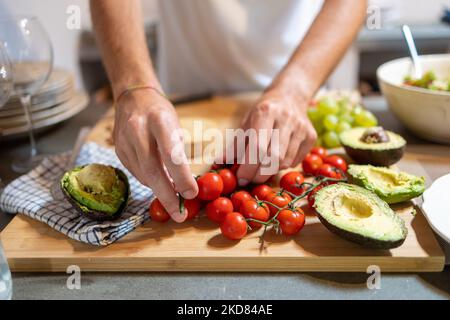 Homme cueillant à la main des tomates cerises pour sa préparation de petit-déjeuner Banque D'Images