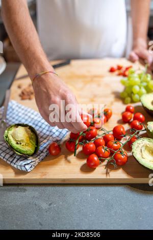 Homme cueillant à la main des tomates cerises pour sa préparation de petit-déjeuner Banque D'Images