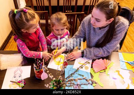 Le volontaire ukrainien Krystyna prépare des décorations de Pâques avec des enfants réfugiés qui se sont échappés de la région de Kharkiv à la sécurité relative de Nadyby, oblast de Lviv, Ukraine sur 21 avril 2022. Depuis que la Fédération de Russie a envahi l'Ukraine, le conflit a forcé plus de 10 millions de personnes à fuir leurs foyers, tant à l'intérieur qu'à l'extérieur. L'église grecque-catholique de Nadyby, près de Lviv, accueille des dizaines de mères avec enfants qui ont fui la guerre dans l'est de l'Ukraine et qui soutient beaucoup plus de réfugiés dans la région. Les familles ont trouvé refuge au Centre de soins pastoraux des prêtres et des moines à Nadyby. (Photo Banque D'Images