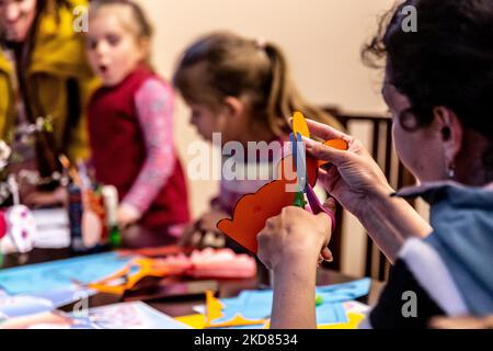 Le volontaire ukrainien Krystyna prépare des décorations de Pâques avec des enfants réfugiés qui se sont échappés de la région de Kharkiv à la sécurité relative de Nadyby, oblast de Lviv, Ukraine sur 21 avril 2022. Depuis que la Fédération de Russie a envahi l'Ukraine, le conflit a forcé plus de 10 millions de personnes à fuir leurs foyers, tant à l'intérieur qu'à l'extérieur. L'église grecque-catholique de Nadyby, près de Lviv, accueille des dizaines de mères avec enfants qui ont fui la guerre dans l'est de l'Ukraine et qui soutient beaucoup plus de réfugiés dans la région. Les familles ont trouvé refuge au Centre de soins pastoraux des prêtres et des moines à Nadyby. (Photo Banque D'Images