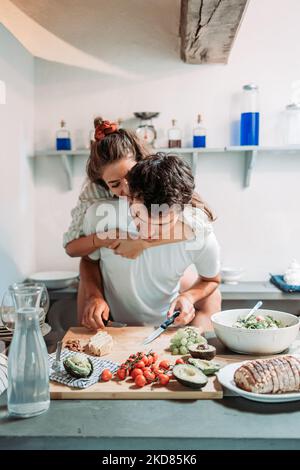 Jeune couple s'amusant dans la cuisine le matin, tout en préparant le petit déjeuner Banque D'Images