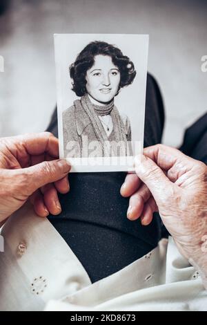 VERS 1970 : mains de femme âgée tenant une photo vintage, noire et blanche de la jeune femme. Concept de passage du temps Banque D'Images