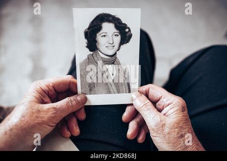 VERS 1970 : mains de femme âgée tenant une photo vintage, noire et blanche de la jeune femme. Concept de passage du temps Banque D'Images