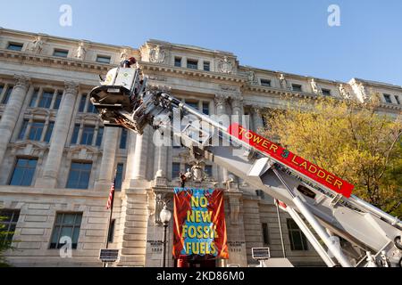 DC Fire utilise un camion à échelle pour atteindre un membre de la rébellion d'extinction après qu'elle a déposé une bannière du deuxième étage du bâtiment John Wilson, où se trouvent les bureaux de la ville de Washington. Pour le jour de la Terre, le groupe a organisé un rassemblement et une marche pour protester contre les combustibles fossiles en général, et pour exiger expressément que la ville refuse de permettre à Washington Gas d'étendre ses infrastructures de distribution de méthane. Elle a été enlevée par le service des incendies de DC et immédiatement arrêtée par la police de DC. La rébellion de l'extinction a refusé de donner son nom. (Photo d'Allison Bailey/NurPhoto) Banque D'Images