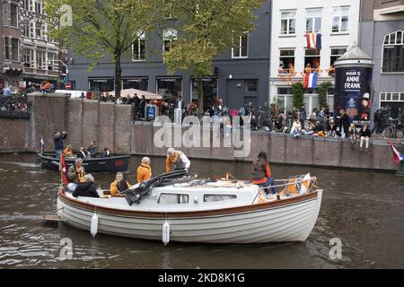 Les pays-Bas célèbrent la Journée du Roi après deux ans d'annulation en raison de la pandémie du coronavirus COVID-19 et des restrictions et mesures de confinement. Des milliers de gens du coin et de visiteurs ont visité les canaux d'Amsterdam pour célébrer avec diverses festivités l'anniversaire du roi Willem-Alexander connu sous le nom de Koningsdag, une fête nationale hollandaise. Tous les types de bateaux et de navires sont vus dans les canaux passant sous les ponts célèbres et près des maisons étroites d'Amsterdam avec des gens sur la danse et d'avoir le plaisir. Les bateaux défilent dans les canaux du centre-ville tandis que les voyageurs se rassemblent dans les rues. Du Banque D'Images
