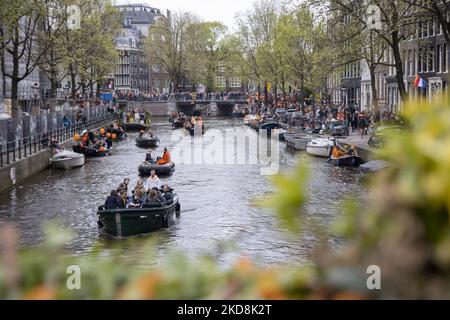 Les pays-Bas célèbrent la Journée du Roi après deux ans d'annulation en raison de la pandémie du coronavirus COVID-19 et des restrictions et mesures de confinement. Des milliers de gens du coin et de visiteurs ont visité les canaux d'Amsterdam pour célébrer avec diverses festivités l'anniversaire du roi Willem-Alexander connu sous le nom de Koningsdag, une fête nationale hollandaise. Tous les types de bateaux et de navires sont vus dans les canaux passant sous les ponts célèbres et près des maisons étroites d'Amsterdam avec des gens sur la danse et d'avoir le plaisir. Les bateaux défilent dans les canaux du centre-ville tandis que les voyageurs se rassemblent dans les rues. Du Banque D'Images