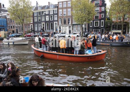 Les pays-Bas célèbrent la Journée du Roi après deux ans d'annulation en raison de la pandémie du coronavirus COVID-19 et des restrictions et mesures de confinement. Des milliers de gens du coin et de visiteurs ont visité les canaux d'Amsterdam pour célébrer avec diverses festivités l'anniversaire du roi Willem-Alexander connu sous le nom de Koningsdag, une fête nationale hollandaise. Tous les types de bateaux et de navires sont vus dans les canaux passant sous les ponts célèbres et près des maisons étroites d'Amsterdam avec des gens sur la danse et d'avoir le plaisir. Les bateaux défilent dans les canaux du centre-ville tandis que les voyageurs se rassemblent dans les rues. Du Banque D'Images