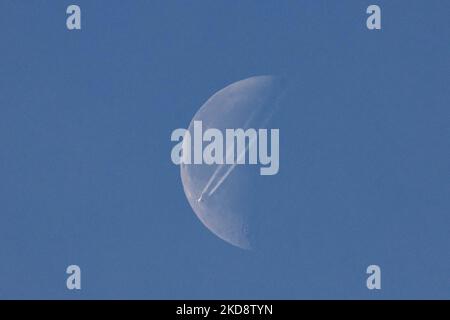Un avion de passagers navigue à 40,000 pieds d'altitude et passe devant la demi-lune, un jour de printemps sans nuages, tandis que l'avion vole au-dessus de l'Europe dans le ciel hollandais. Moonpass est le but ultime des photographes d'aviation, les planespotters. Pendant le vol, le jet passager laisse derrière lui des contrailles ou un sentier de condensation, une ligne de vapeur blanche qui passe devant le satellite naturel de la Terre et l'objet céleste le plus proche de l'univers. Eindhoven, pays-Bas sur 24 avril 2022. (Photo de Nicolas Economou/NurPhoto) Banque D'Images