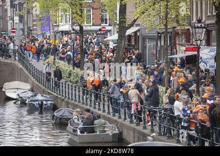 Des foules de personnes portant principalement des vêtements orange et ayant le drapeau hollandais comme vu dans les rues d'Amsterdam tandis que les pays-Bas célèbrent la Journée du Roi après deux ans d'annulation en raison de la pandémie du coronavirus COVID-19 et des restrictions et mesures de verrouillage. Des milliers de gens du coin, de fêtards et de visiteurs ont visité le centre-ville, les parcs près du Rijksmuseum, les canaux d'Amsterdam pour célébrer avec diverses festivités l'anniversaire du roi Willem-Alexander connu sous le nom de Koningsdag, une fête nationale néerlandaise. Tous les types de bateaux et de bateaux sont vus dans les canaux passant sous les ponts célèbres Banque D'Images