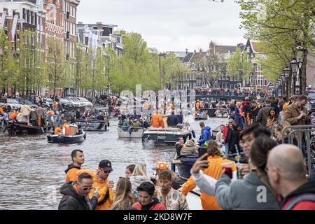 Les gens dansent, fêtent et s'amusent après avoir pris un verre d'alcool devant les bars et les canaux. Des foules de personnes portant principalement des vêtements orange et ayant le drapeau hollandais comme vu dans les rues d'Amsterdam tandis que les pays-Bas célèbrent la Journée du Roi après deux ans d'annulation en raison de la pandémie du coronavirus COVID-19 et des restrictions et mesures de verrouillage. Des milliers de gens du coin, de fêtards et de visiteurs ont visité le centre-ville, les parcs près du Rijksmuseum, les canaux d'Amsterdam pour célébrer avec diverses festivités l'anniversaire du roi Willem-Alexander connu sous le nom de Koningsdag, un hollandais n Banque D'Images