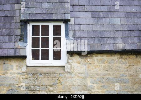 Détail du vieux cottage en Angleterre, Royaume-Uni, avec des murs en pierre et une fenêtre de dortoirs dans un toit en ardoise Banque D'Images