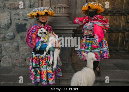 Les jeunes filles quechua habillées traditionnellement avec de jeunes lamas et agneau, s'asseoir à l'extérieur d'une église dans le centre de Cusco, attendant que les touristes posent pour des photos. Le dimanche 17 avril 2022, à Cusco, Pérou. (Photo par Artur Widak/NurPhoto) Banque D'Images