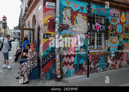 Les gens s'assoient près de la fresque peinte sur le mur à Kazimierz, quartier juif historique, à Cracovie, en Pologne, sur 11 mai 2022. (Photo de Jakub Porzycki/NurPhoto) Banque D'Images