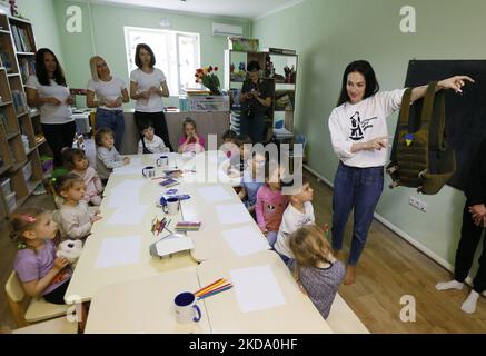 Un volontaire ukrainien (R) montre une veste à l'épreuve des balles avec des chevrons pour les enfants déplacés à Odesa, en Ukraine, le 13 mai 2022. Les enfants ukrainiens déplacés des régions du pays les hostilités ont maintenant lieu dessiner des images. Les photos des enfants seront utilisées par les volontaires pour fabriquer des chevrons pour les uniformes des soldats ukrainiens. (Photo par STR/NurPhoto) Banque D'Images