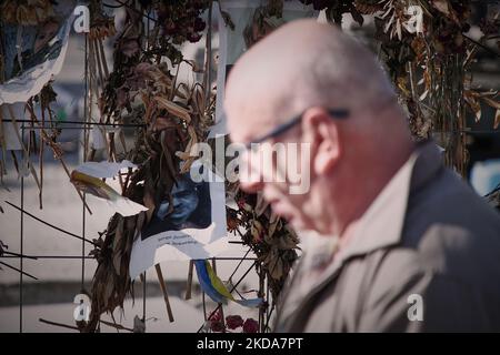 Les gens marchent devant un mur de fleurs avec des photos des victimes ukrainiennes de l'invasion russe à Varsovie, Pologne, le 17 mai 2022. Le conflit a causé environ 8000 mille victimes et plus de 6 millions de redevances dans ce que l'ONU a appelé la plus grande crise humanitaire en Europe depuis les guerres yougoslaves de 1990s. (Photo par STR/NurPhoto) Banque D'Images