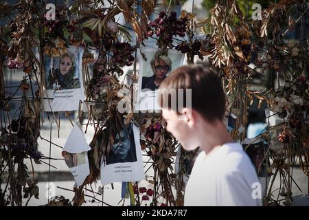 Les gens marchent devant un mur de fleurs avec des photos des victimes ukrainiennes de l'invasion russe à Varsovie, Pologne, le 17 mai 2022. Le conflit a causé environ 8000 mille victimes et plus de 6 millions de redevances dans ce que l'ONU a appelé la plus grande crise humanitaire en Europe depuis les guerres yougoslaves de 1990s. (Photo par STR/NurPhoto) Banque D'Images