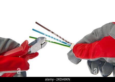 Mains dans des gants de protection avec coupe-fil et câble isolé sur fond blanc. Un électricien coupe un fil de cuivre à trois conducteurs avec des coupe-fils Banque D'Images