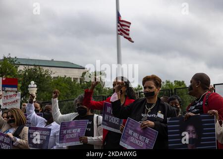 Un drapeau américain vole à la moitié du personnel à l'extérieur de la Cour suprême à Washington, D.C., sur 25 mai 2022, un jour après une fusillade de masse dans une école à Uvalde, Texas, alors que les femmes tiennent leurs poings dans les airs lors d'un rassemblement et d'une protestation silencieuse exigeant des droits de reproduction et de vote (Photo de Bryan Olin Dozier/NurPhoto) Banque D'Images