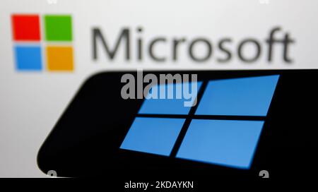 Le logo Windows affiché sur l'écran d'un téléphone et le logo Microsoft affiché sur un écran en arrière-plan sont illustrés sur cette photo prise à Cracovie, en Pologne, sur 26 mai 2022. (Photo Illustration par Jakub Porzycki/NurPhoto) Banque D'Images