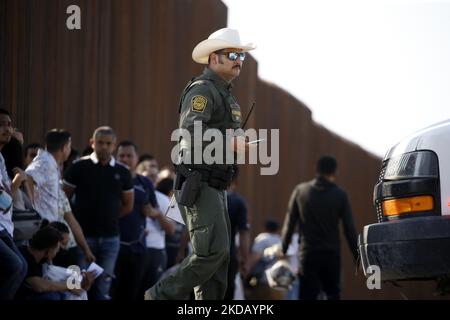 Un agent de la patrouille frontalière passe devant des migrants qui attendent d'être transportés dans un centre de détention de 26 mai 2022, à Eagle Pass, Texas, États-Unis. Titre 42, le mandat de l'ère Trump qui a été fixé pour empêcher les migrants d'entrer aux États-Unis, Devait expirer sur 23 mai mais a été bloqué par une poursuite déposée par plusieurs États citant que la décision d'attaquer la loi "n'a pas satisfait aux normes fixées par la Loi sur la procédure administrative" et qu'il n'y a pas de solution permanente pour gérer l'inévitable augmentation de l'immigration. Les opposants au maintien de la loi ont exprimé leurs revendications en affirmant que le titre 42 est illégal en ce qu'il viole Banque D'Images