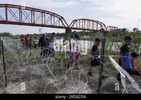 Les migrants, la plupart avec des enfants suivent un chemin le long du fil de la concertina où ils seront placés sous la garde par la patrouille frontalière après avoir traversé le Rio Grande sur 27 mai 2022 à Eagle Pass Texas, États-Unis. Titre 42, le mandat de l'ère Trump qui a été fixé pour empêcher les migrants d'entrer aux États-Unis, Devait expirer sur 23 mai mais a été bloqué par une poursuite déposée par plusieurs États citant que la décision d'attaquer la loi "n'a pas satisfait aux normes fixées par la Loi sur la procédure administrative" et qu'il n'y a pas de solution permanente pour gérer l'inévitable augmentation de l'immigration. Les opposants à la défense de Banque D'Images