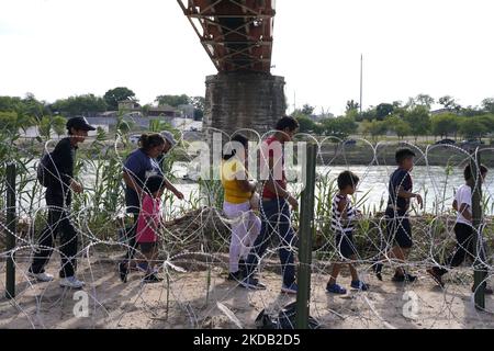 Les migrants, la plupart avec des enfants suivent un chemin le long du fil de la concertina où ils seront placés sous la garde par la patrouille frontalière après avoir traversé le Rio Grande sur 27 mai 2022 à Eagle Pass Texas, États-Unis. Titre 42, le mandat de l'ère Trump qui a été fixé pour empêcher les migrants d'entrer aux États-Unis, Devait expirer sur 23 mai mais a été bloqué par une poursuite déposée par plusieurs États citant que la décision d'attaquer la loi "n'a pas satisfait aux normes fixées par la Loi sur la procédure administrative" et qu'il n'y a pas de solution permanente pour gérer l'inévitable augmentation de l'immigration. Les opposants à la défense de Banque D'Images