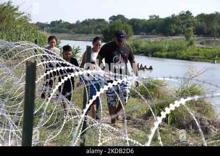 Les migrants, la plupart avec des enfants suivent un chemin le long du fil de la concertina où ils seront placés sous la garde par la patrouille frontalière après avoir traversé le Rio Grande sur 27 mai 2022 à Eagle Pass Texas, États-Unis. Titre 42, le mandat de l'ère Trump qui a été fixé pour empêcher les migrants d'entrer aux États-Unis, Devait expirer sur 23 mai mais a été bloqué par une poursuite déposée par plusieurs États citant que la décision d'attaquer la loi "n'a pas satisfait aux normes fixées par la Loi sur la procédure administrative" et qu'il n'y a pas de solution permanente pour gérer l'inévitable augmentation de l'immigration. Les opposants à la défense de Banque D'Images