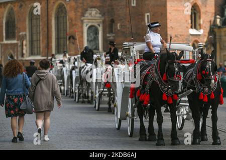 Des calèches attendent des clients sur la place principale de Cracovie, classée au patrimoine mondial de l'UNESCO. Cracovie, l'une des principales destinations touristiques d'Europe, classée au patrimoine mondial de l'UNESCO, est la deuxième plus grande ville de Pologne et l'ancienne capitale du Royaume historique de Pologne. Dimanche, 29 mai 2022, à Cracovie, en Pologne. (Photo par Artur Widak/NurPhoto) Banque D'Images