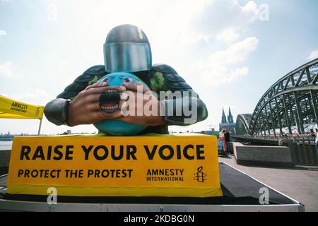 Un flotteur avec une police couvrant l'embouchure de la planète est vu derrière la cathédrale de la Cologne à Cologne, en Allemagne, sur 4 juin 2022, lors de l'action "élever votre voix" d'Amnesty international Koeln. (Photo de Ying Tang/NurPhoto) Banque D'Images