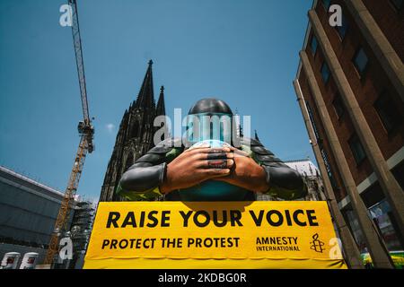 Un flotteur avec une police couvrant l'embouchure de la planète est vu derrière la cathédrale de la Cologne à Cologne, en Allemagne, sur 4 juin 2022, lors de l'action "élever votre voix" d'Amnesty international Koeln. (Photo de Ying Tang/NurPhoto) Banque D'Images