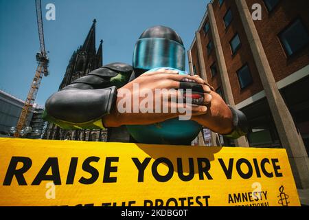 Un flotteur avec une police couvrant l'embouchure de la planète est vu derrière la cathédrale de la Cologne à Cologne, en Allemagne, sur 4 juin 2022, lors de l'action "élever votre voix" d'Amnesty international Koeln. (Photo de Ying Tang/NurPhoto) Banque D'Images