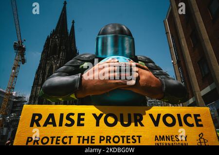 Un flotteur avec une police couvrant l'embouchure de la planète est vu derrière la cathédrale de la Cologne à Cologne, en Allemagne, sur 4 juin 2022, lors de l'action "élever votre voix" d'Amnesty international Koeln. (Photo de Ying Tang/NurPhoto) Banque D'Images