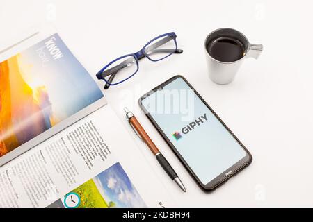 Dans cette illustration photo, un logo Giphy vu sur un écran de smartphone sur un bureau à côté d'un café, d'un stylo, de lunettes et d'un magazine à Athènes, Grèce sur 5 juin 2022. (Photo Illustration par Nikolas Kokovlis/NurPhoto) Banque D'Images