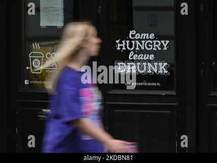 Une femme passe devant un bar local dans le centre de Cracovie. L'inflation annuelle en Pologne s'est accélérée pour atteindre 13,9% en mai 2022, contre 12,4% en avril 2022. C'est la plus haute lecture depuis 1997, avec une forte augmentation des prix mondiaux des matières premières causée par la guerre russo-ukrainienne. La pression principale provenait des carburants pour les équipements de transport, suivis par les prix de l'électricité, du gaz et d'autres carburants, puis des aliments et des boissons non alcoolisées. Mardi, 07 juin 2022, à Cracovie, en Pologne. (Photo par Artur Widak/NurPhoto) Banque D'Images