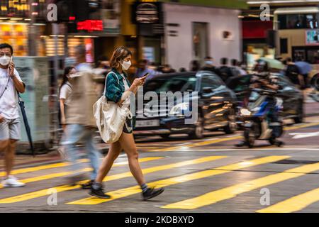 Hong Kong, Chine, 11 juin 2022, Une jeune femme masquée traverse une rue à Mongkok dans un tir panoramique. (Photo de Marc Fernandes/NurPhoto) Banque D'Images