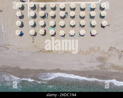 Images aériennes d'un drone de la côte de la ville de Rethymno avec la longue plage et les bars de plage de l'île de Creta. Les gens sont vus profiter du soleil sous le parapluie au bar de la plage ou nager dans la mer cristalline. Rethymno est une ville balnéaire méditerranéenne historique située sur la côte nord de la Crète, au bord de la mer Égée, avec une population de 40,000 personnes. Une destination touristique avec un port et une ville vénitienne historique, des sites archéologiques, des plages de sable sans fin, des sports nautiques, de belles tavernes traditionnelles et une grande variété d'hôtels. Le tourisme rebondit avec des réservations dépassant Banque D'Images