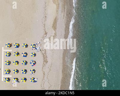 Images aériennes d'un drone de la côte de la ville de Rethymno avec la longue plage et les bars de plage de l'île de Creta. Les gens sont vus profiter du soleil sous le parapluie au bar de la plage ou nager dans la mer cristalline. Rethymno est une ville balnéaire méditerranéenne historique située sur la côte nord de la Crète, au bord de la mer Égée, avec une population de 40,000 personnes. Une destination touristique avec un port et une ville vénitienne historique, des sites archéologiques, des plages de sable sans fin, des sports nautiques, de belles tavernes traditionnelles et une grande variété d'hôtels. Le tourisme rebondit avec des réservations dépassant Banque D'Images