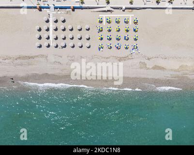 Images aériennes d'un drone de la côte de la ville de Rethymno avec la longue plage et les bars de plage de l'île de Creta. Les gens sont vus profiter du soleil sous le parapluie au bar de la plage ou nager dans la mer cristalline. Rethymno est une ville balnéaire méditerranéenne historique située sur la côte nord de la Crète, au bord de la mer Égée, avec une population de 40,000 personnes. Une destination touristique avec un port et une ville vénitienne historique, des sites archéologiques, des plages de sable sans fin, des sports nautiques, de belles tavernes traditionnelles et une grande variété d'hôtels. Le tourisme rebondit avec des réservations dépassant Banque D'Images