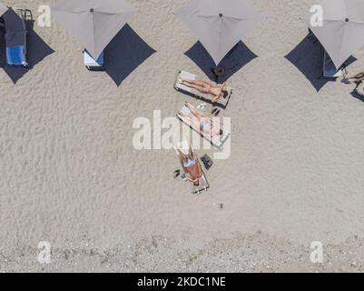 Images aériennes d'un drone de la côte de la ville de Rethymno avec la longue plage et les bars de plage de l'île de Creta. Les gens sont vus profiter du soleil sous le parapluie au bar de la plage ou nager dans la mer cristalline. Rethymno est une ville balnéaire méditerranéenne historique située sur la côte nord de la Crète, au bord de la mer Égée, avec une population de 40,000 personnes. Une destination touristique avec un port et une ville vénitienne historique, des sites archéologiques, des plages de sable sans fin, des sports nautiques, de belles tavernes traditionnelles et une grande variété d'hôtels. Le tourisme rebondit avec des réservations dépassant Banque D'Images