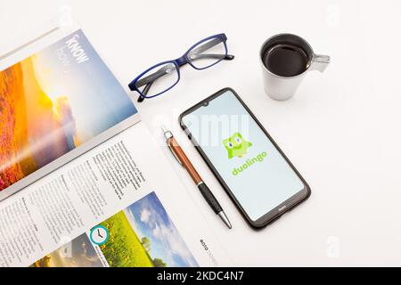 Dans cette illustration photo, un logo Duolingo vu sur un écran de smartphone sur un bureau à côté d'un café, d'un stylo, de lunettes et d'un magazine à Athènes, Grèce sur 15 juin 2022. (Photo de Nikolas Kokovovlis/NurPhoto) Banque D'Images