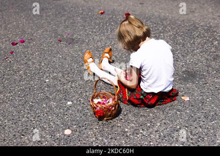 Une fille s'assoit dans une rue pendant la procession de Corpus Christi à Andrychow, en Pologne, sur 16 juin 2022. La procession commence par un prêtre portant une Monstruce sous une verrière. Les fidèles le suivent en chantant des hymnes religieux, tandis que les jeunes filles vêtues de robes régionales blanches ou traditionnelles dispersent les pétales de fleurs le long du parcours. Corpus Christi est une fête mobilier catholique commémorant la Transubstitution. (Photo de Beata Zawrzel/NurPhoto) Banque D'Images