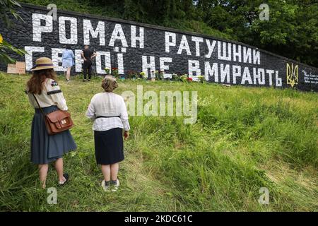 Les femmes prient près des graffitis peints en mémoire du soldat et activiste Roman Ratushnyi, Kiev, Ukraine, 16 juin 2022. (Photo par Oleksandr Khomenko/NurPhoto) Banque D'Images