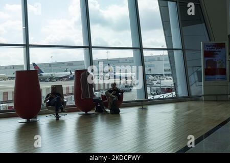 Passagers assis devant un Boeing 737-800 de Ryanair et un Boeing 767 de Delta Air Lines. Le matin, les passagers partant et arrivant sont vus porter leurs bagages à l'intérieur du terminal et de la zone des portes de l'aéroport de Bruxelles Zaventem BRU, dans la capitale belge. Les départs et les arrivées sont combinés dans le même secteur. De nombreux aéroports européens ont souffert de retards et d'annulations de vols en raison de la vague de pénurie de personnel et des grèves pendant la saison de voyage d'été très chargée avec une demande accrue de voyages aériens, une reprise pour l'industrie de l'aviation, les voyagistes et les compagnies aériennes après le Covid-19 Coronavi Banque D'Images