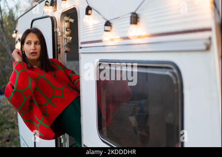 Une femme caucasienne en pull tricoté rouge surdimensionné voyage à motorhome en automne. Banque D'Images