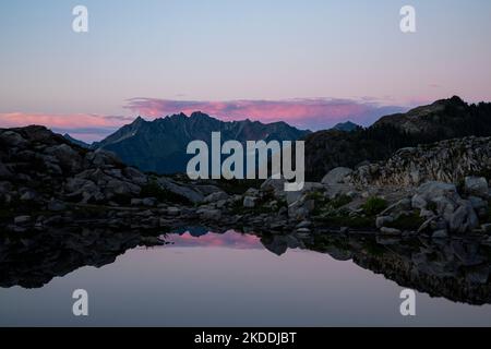 WA22701-00...WASHINGTON - coucher de soleil sur les nuages au-dessus de la montagne Goat se reflétant dans un tarn sur la crête de Kulshan, dans l'aire de loisirs de Heather Meadows. Banque D'Images