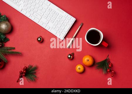un bureau avec un clavier, des oranges et des décorations de noël sur la table à côté est une tasse de café Banque D'Images